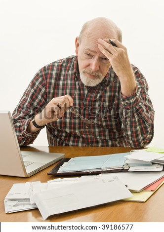Retired senior male at his desk worrying how he will pay the bills.
