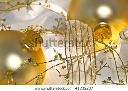 Glowing golden Christmas ornaments with translucent ribbons, sparkling gold stars and twinkling white lights. Short depth of field with glowing effects. Good for Christmas card or background.