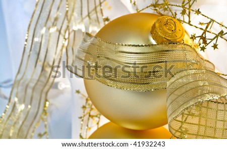 Glowing golden Christmas ornaments with translucent ribbons, sparkling gold stars and twinkling white lights. Short depth of field with glowing effects. Good for Christmas card or background.