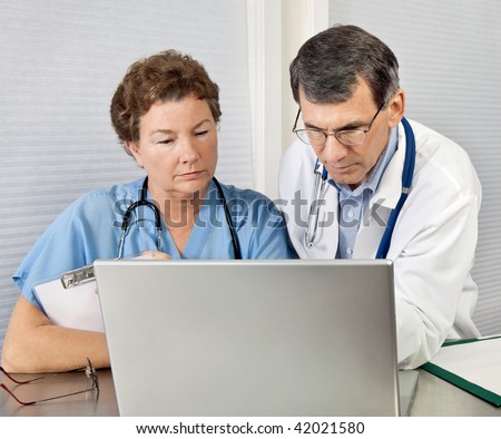 Doctor and nurse reviewing patient information on a laptop computer in an office setting