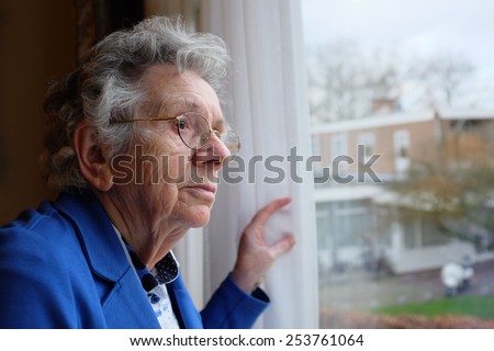 Elderly woman looks out a window