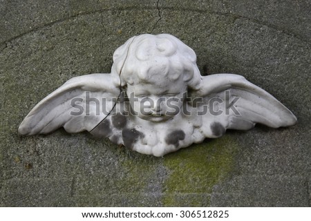 Little angel on a headstone, broken and weathered