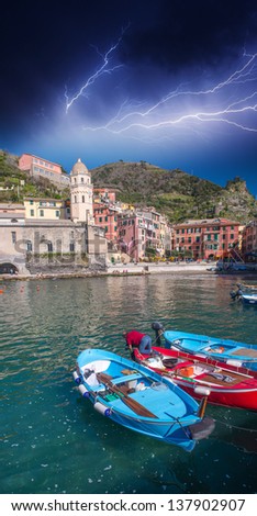 Colorful boats in the quaint port of Vernazza with storm, Cinque Terre - Italy.