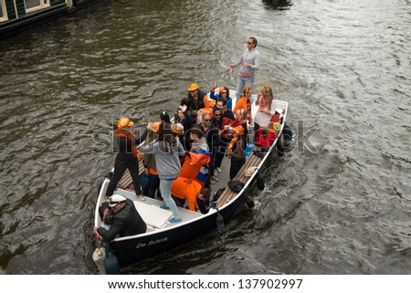 AMSTERDAM - APRIL 30: Amsterdam canals full of boats and people in orange during the celebration of queensday on April 30, 2013 in Amsterdam, The Netherlands.