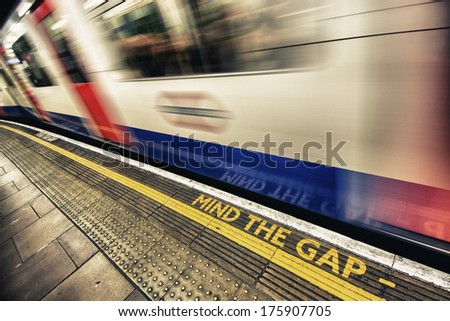 Mind the gap sign with speeding train in London underground.