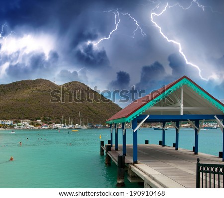 Thunderstorm over beautiful beach with jetty over water.