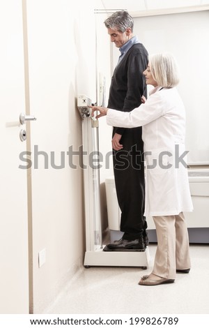 Man standing on weight machine with female doctor analyzing results.