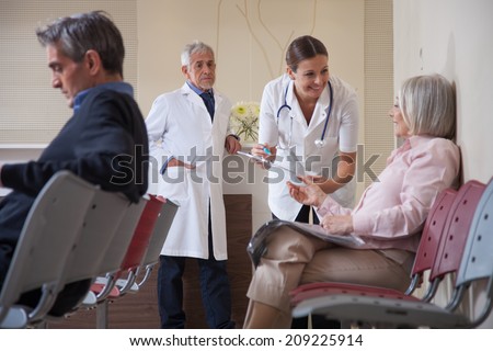 Female doctor talking to patient in waiting room.