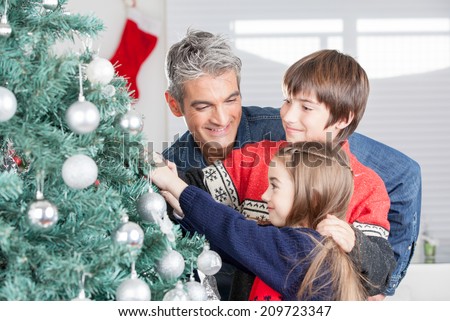 Father with son and daughter decorating Christmas tree. Family Christmas concept.