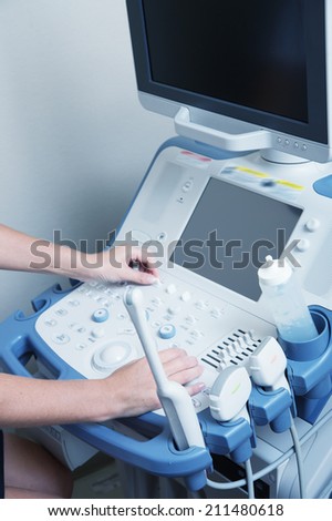 Ultrasound scanner machine with female hands controlling it.