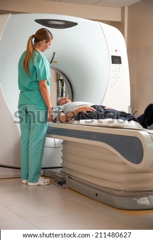 Open MRI scanner with man in 40s undergoing test.