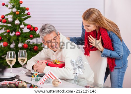 Man in 40s hiding Christmas gift to his wife. Joking and relaxing holiday concept.