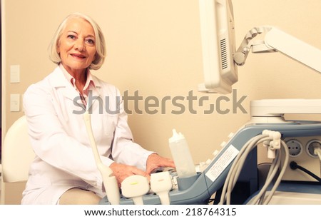 Happy mature female doctor using ultrasound scanner. Echography machine.