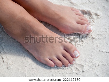 Relaxing at a beach, with beautiful woman feet in the warm sand.