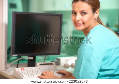 Beautiful female doctor checking data at computer terminal.