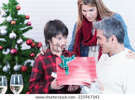 Child receiving Christmas gift from parents at home.