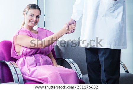 Happy female patient handshaking male doctor.