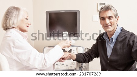 Male patient undergoing wrist ultrasound with female doctor.