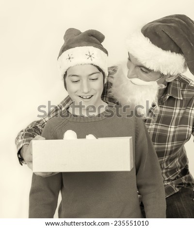 Surprised son receiving Christmas gift from his father. Happy family with red hat isolated on white.