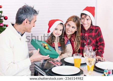 Father receiving Christmas gift from his family at home. Happy holiday concept.