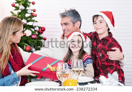 Wife receiving Christmas present from her husband and children. Happy family concept.