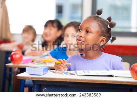 Row of students in a primary interracial classroom. Afro american girl paying attention to the teacher.