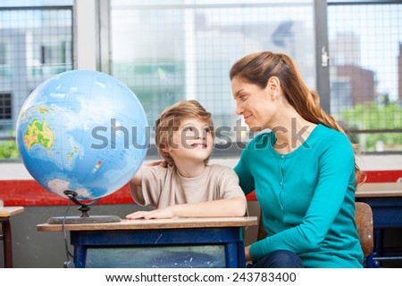 Happy kid at primary school learning world geography with teacher.
