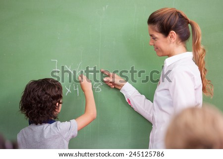 Teacher questioning kid at chalkboard.