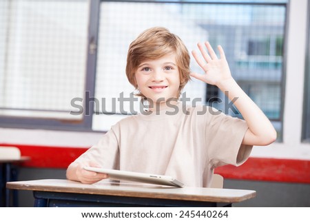 Caucasian kid raising hand at school.