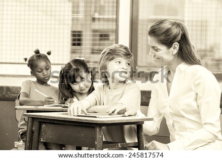 Kid learning to use tablet with teacher with classmates colouring books. Multiracial classroom concept.