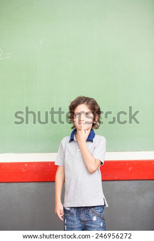 Elementary school student at chalkboard thinking about the answer.