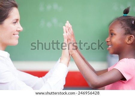 Happy african schoolgirl and female teacher doing high five after math lesson.