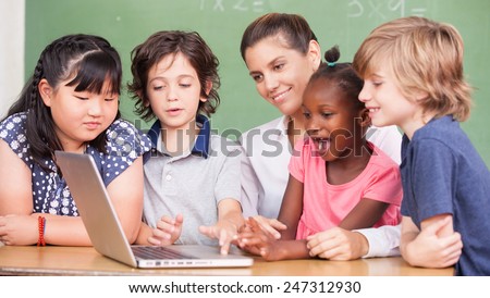 Happy primary class concept. Students learning computer science with female teacher.