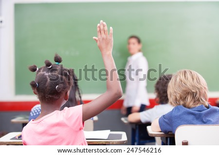 Afroamerican female student raising hand at school.