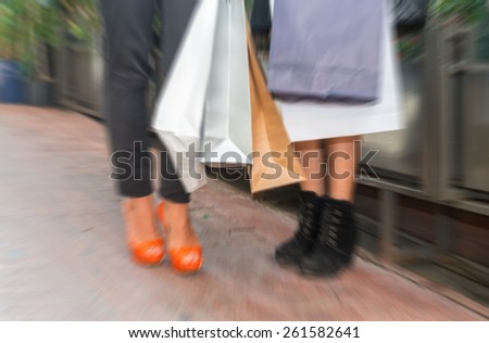 Blurred picture of women making shopping, legs detail.