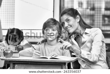 Smiling teacher pointing her finger to something during a school lesson.