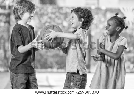Black and white scene of children playing basketball at school.