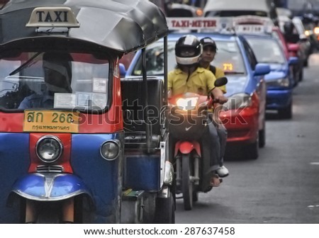 BANGKOK - AUG 23: A three wheeled tuk tuk taxi transports passengers along road, August 23, 2012 in Bangkok, Thailand. Tuk tuks can be hired from as little as $1 or B30 a fare for short trips