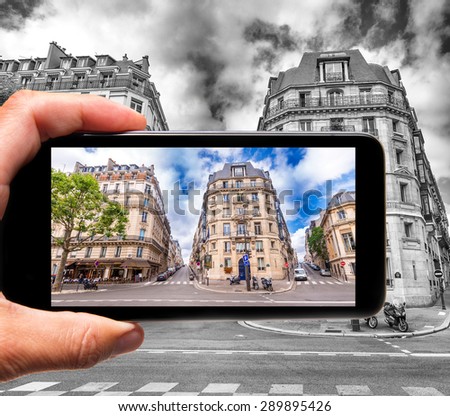 Taking colors out of black and white. Female hand with smartphone taking a picture of Paris. Tourism concept.