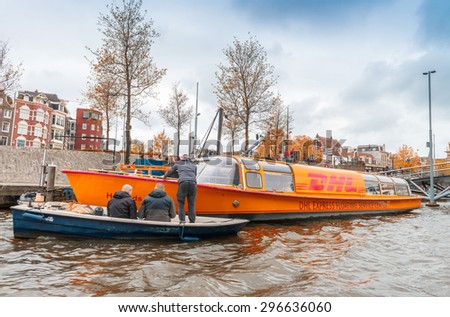 AMSTERDAM, APRIL 15, 2015: DHL post company boat delivering mail in the city centre of Amsterdam.