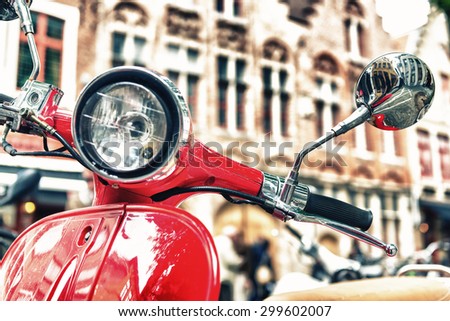 Old fashioned red motorbike parked in city center.
