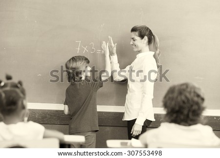 Teacher congratulating with kid in primary classroom.