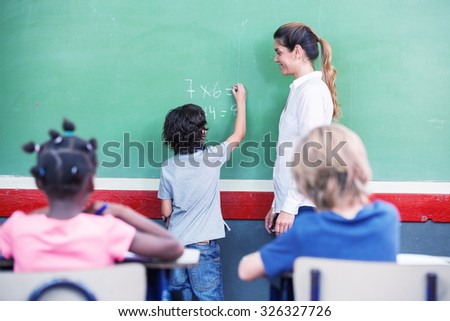 Kid writing math at chalkboard.