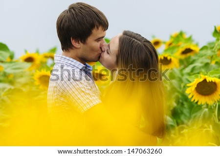 young girl and a young man in a field of sunflowers