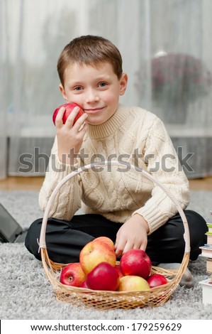 boy with apples and books  at home on the carpet