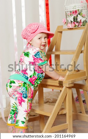 baby girl in a fashionable suit, cap and rubber boots