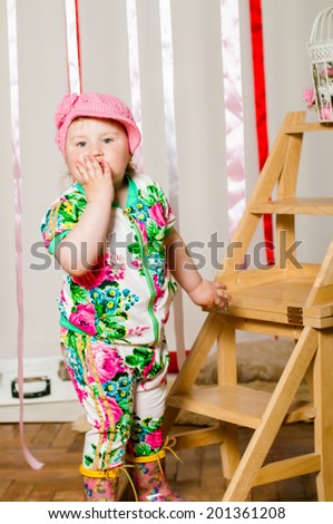 Baby girl in a fashionable suit, cap and rubber boots
