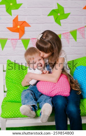 Little boy and an older sister smiling on the bench with the spring decor