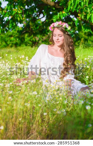 Girl with long hair on the field with daisies in summer