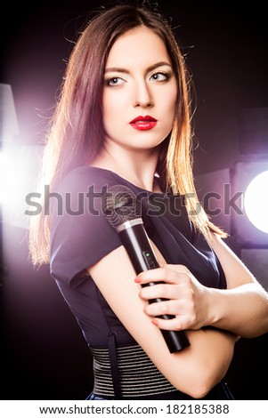Close-up portrait of beautiful elegant young woman with microphone